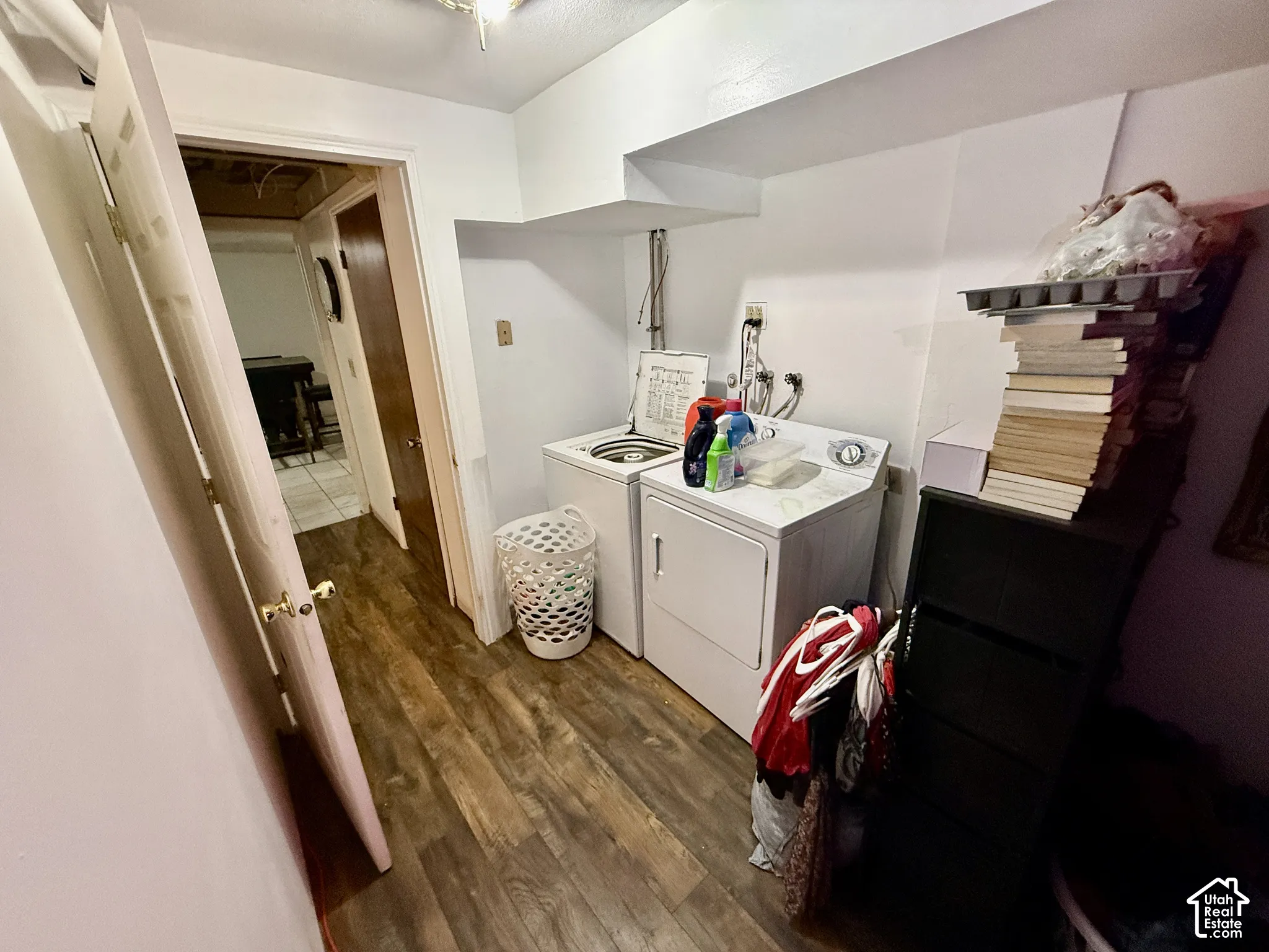 Laundry area featuring wood-finish flooring, white walls, and a built-in shelf