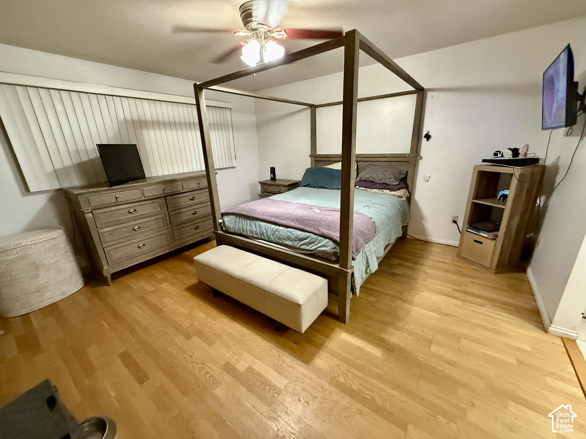 Hardwood flooring throughout, with a ceiling fan light fixture and horizontal window blinds
