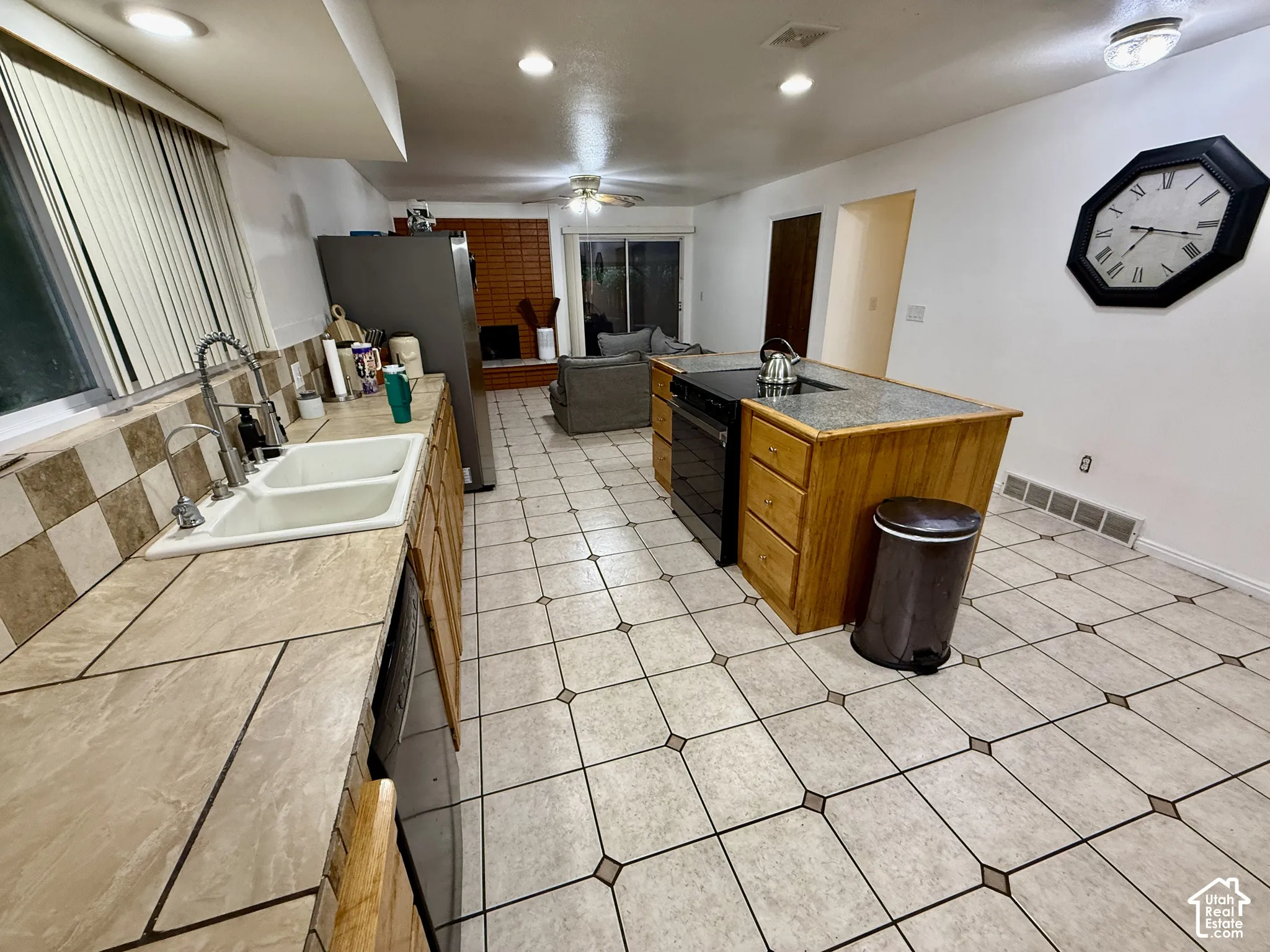 Kitchen with tile flooring, wood cabinetry, built-in dishwasher, and a center island featuring a cooktop