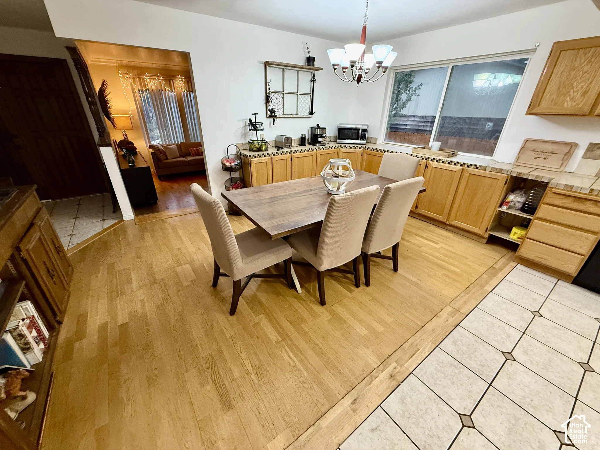 Hardwood flooring, oak cabinetry, tiled countertops, chandelier lighting, and a large window