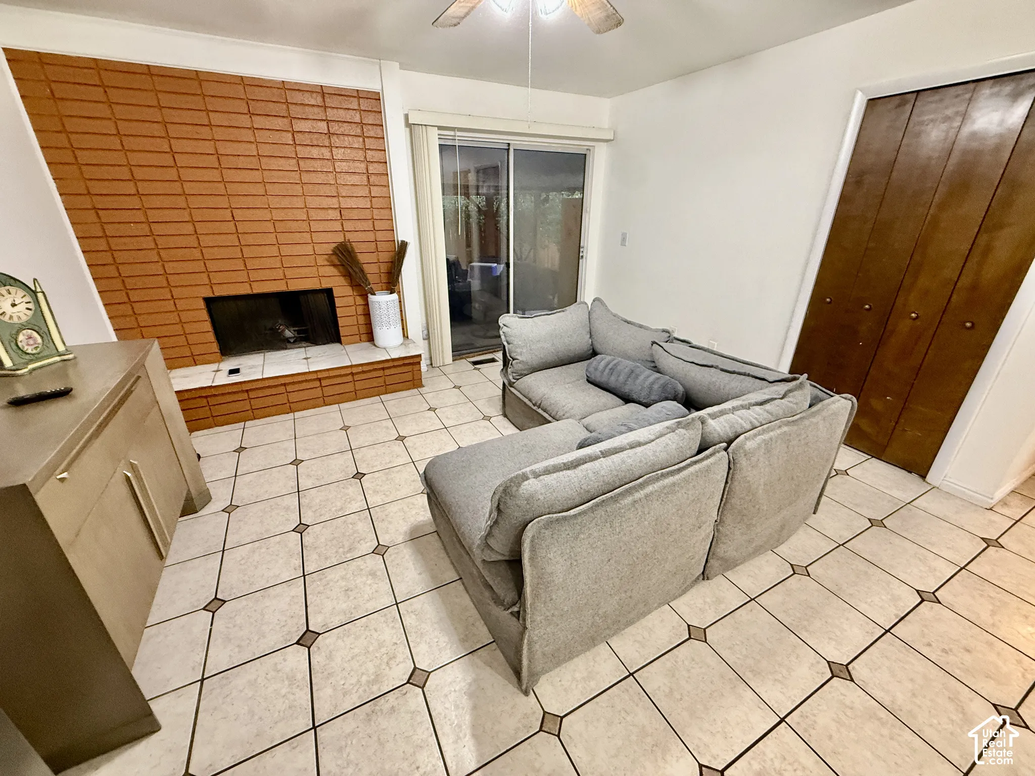 Tiled flooring, brick fireplace, wood bifold doors, sliding glass door, ceiling fan