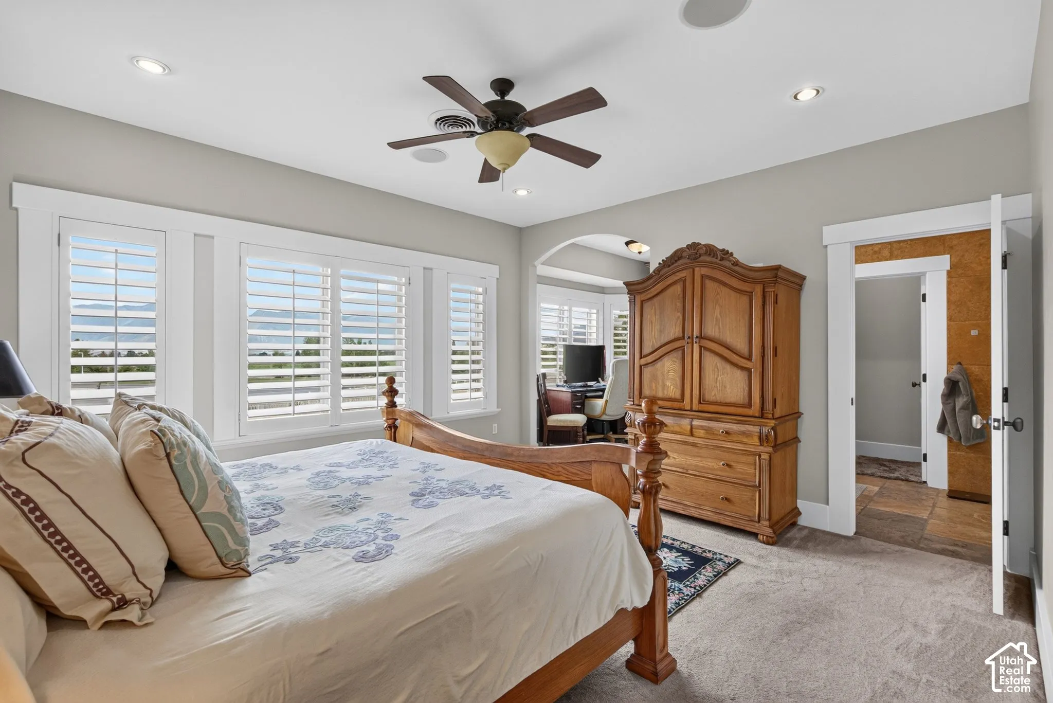 Recessed lighting, ceiling fan, and multiple windows with plantation shutters