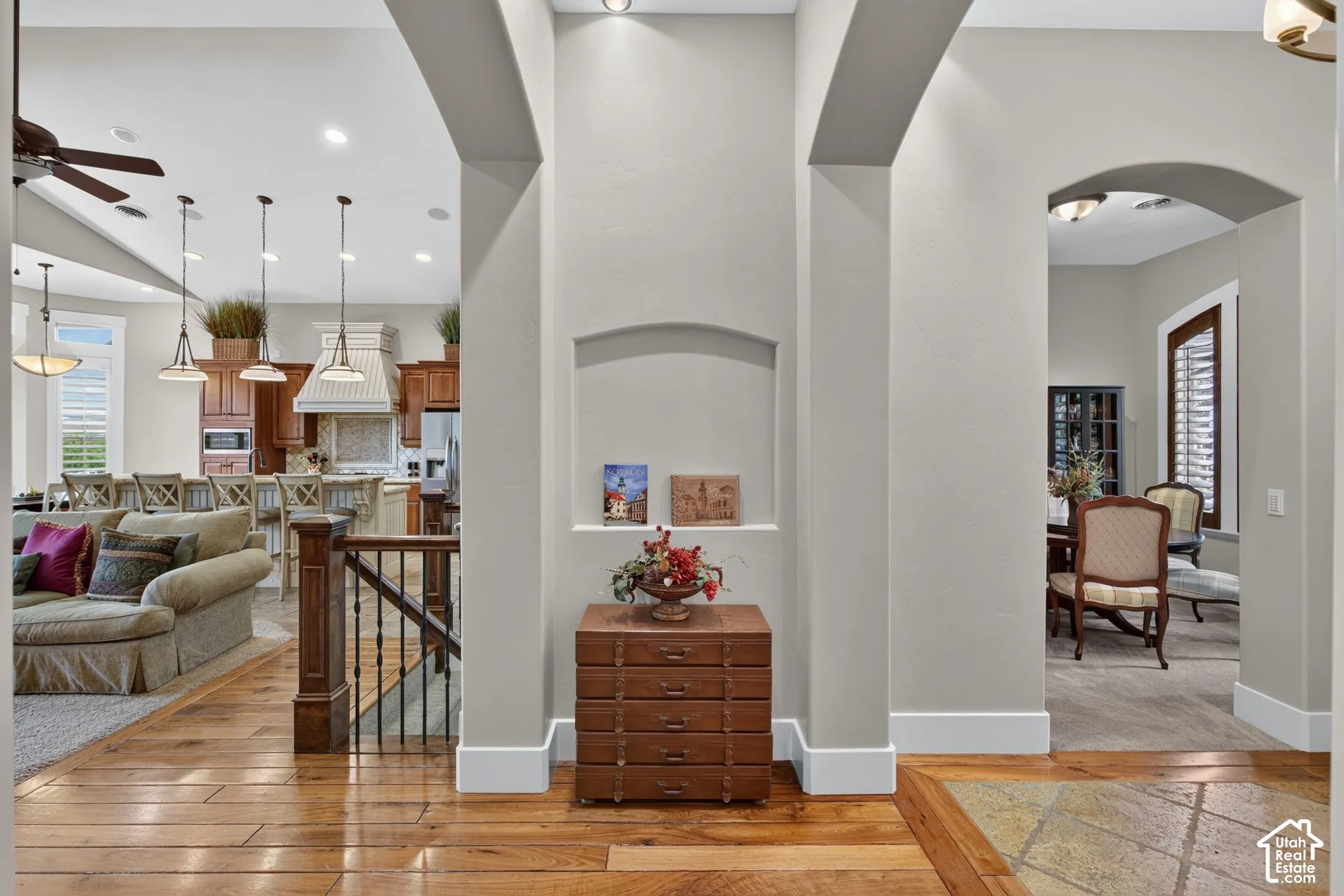Hardwood flooring with a decorative inlay, arched doorways, built-in wall niche, and an open-concept living area with a kitchen