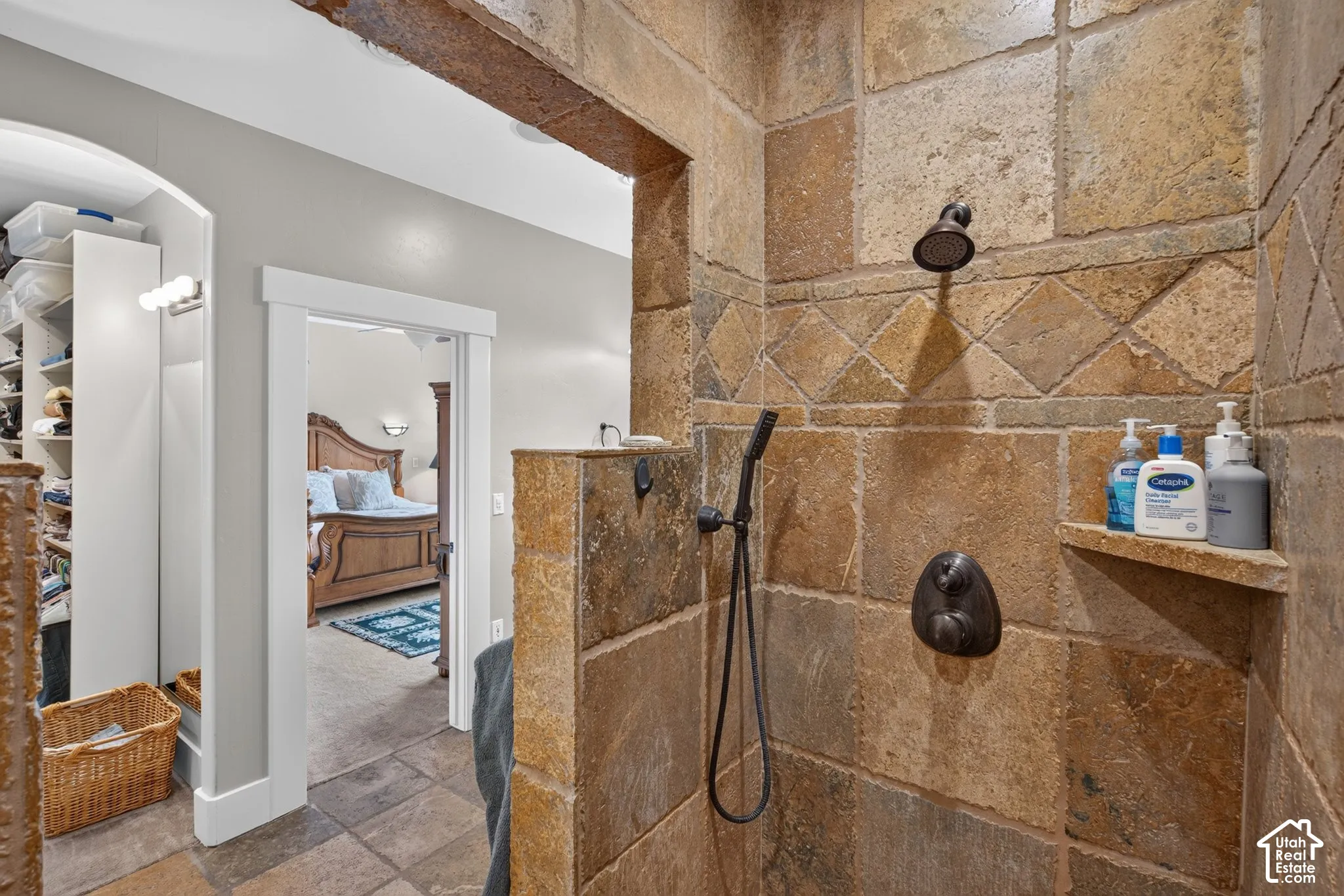 Stone-tiled shower with a built-in shelf, rainfall showerhead, and a handheld shower fixture
