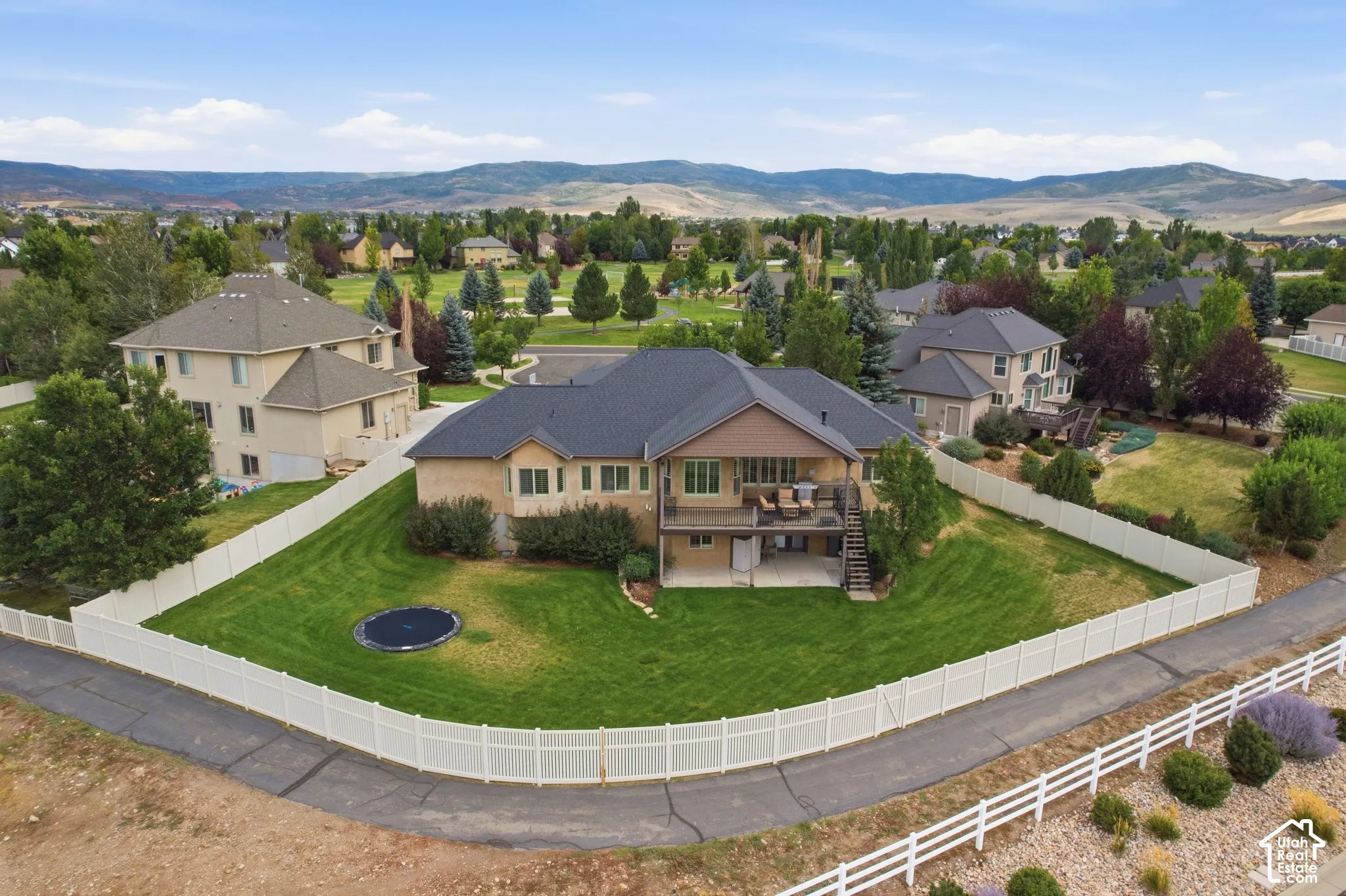 Expansive fenced yard with mature landscaping and a multi-level deck