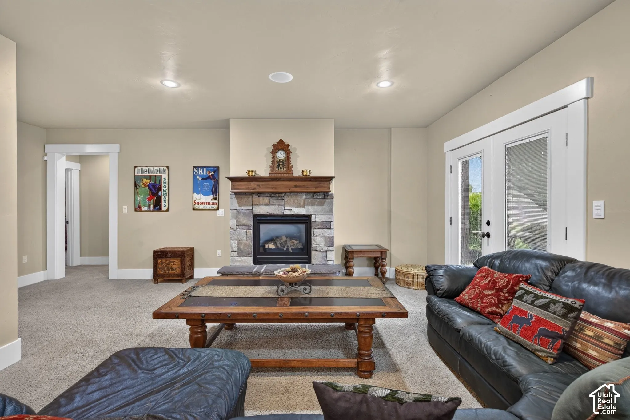 Stone-clad fireplace with wood mantel, recessed lighting, double French doors, and neutral wall paint
