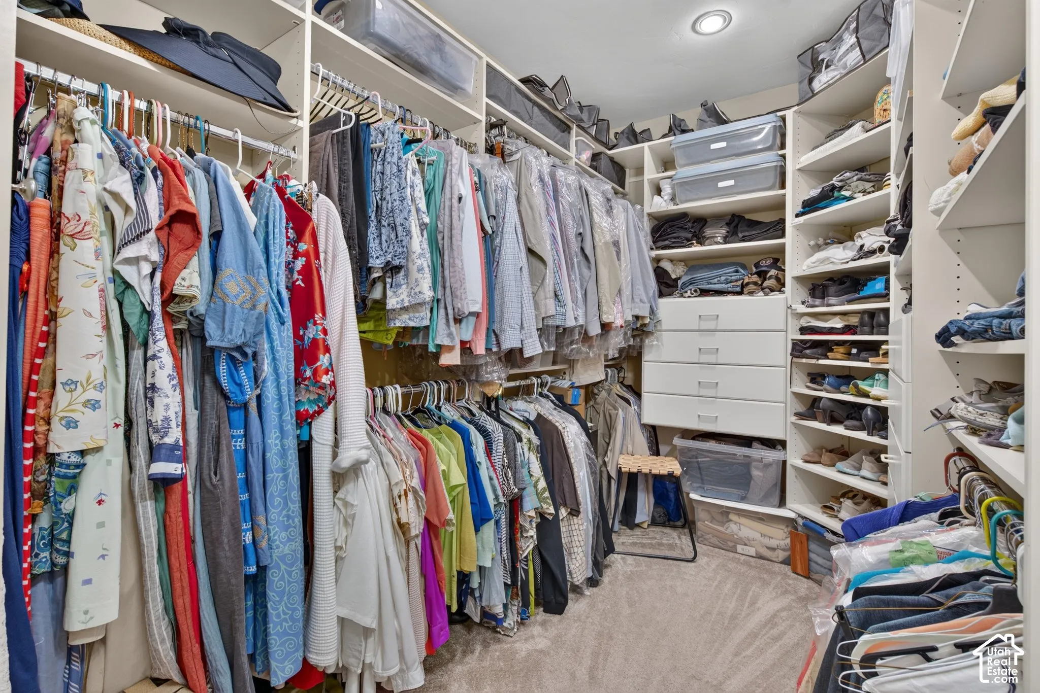 Custom closet system featuring extensive shelving, multiple hanging rods, built-in drawers, and recessed lighting