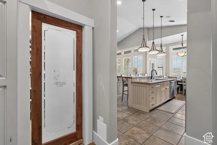 Kitchen island with integrated sink, stainless steel dishwasher, and pendant lighting