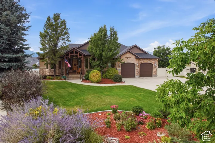 Stone and siding exterior with an attached two-car garage, mature landscaping, and a covered front entry