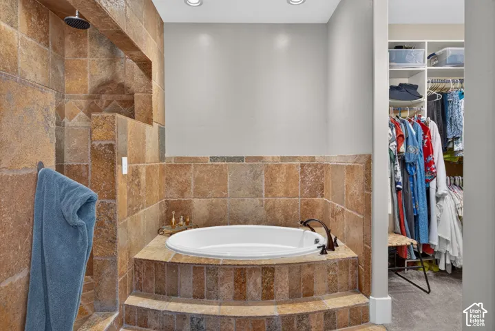 Built-in soaking tub with bronze-finish fixtures, a full tile surround, and recessed lighting