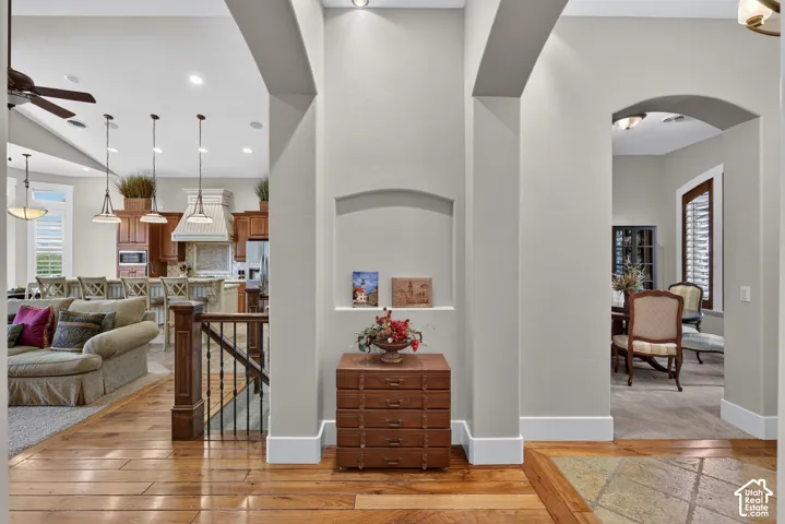 Hardwood flooring with a decorative inlay, arched doorways, built-in wall niche, and an open-concept living area with a kitchen