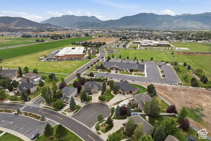 Residential neighborhood with mature landscaping, surrounded by open green spaces and distant mountains