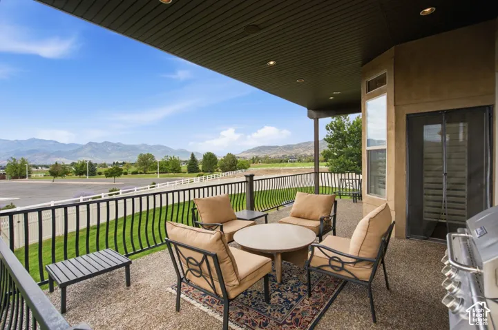 Covered outdoor patio with a textured concrete surface, recessed lighting, and a black wrought iron railing