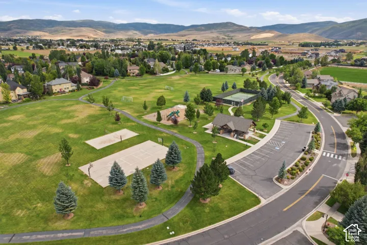 Expansive community park featuring a large green space, tennis court, basketball courts, and a playground area