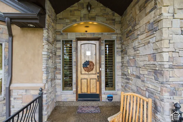 Stone veneer exterior with wood-finish entry door, recessed lighting, and sidelight windows