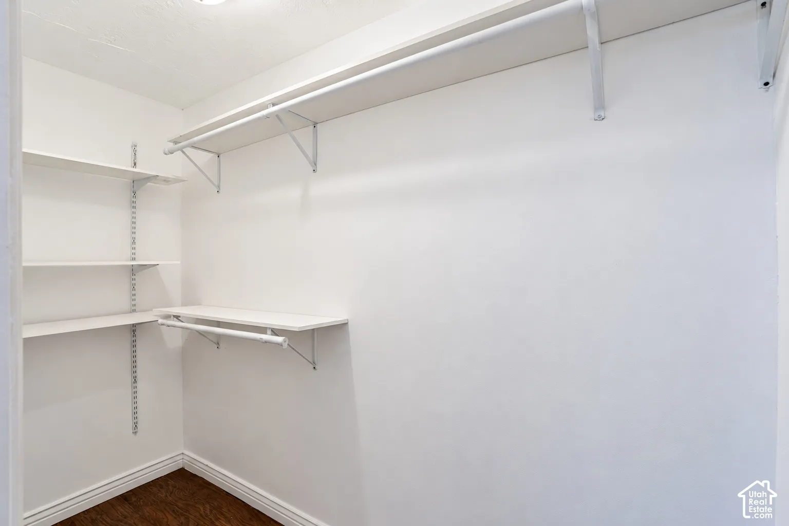 Primary bedroom walk-in closet with adjustable shelving, built-in hanging rods, and new paint