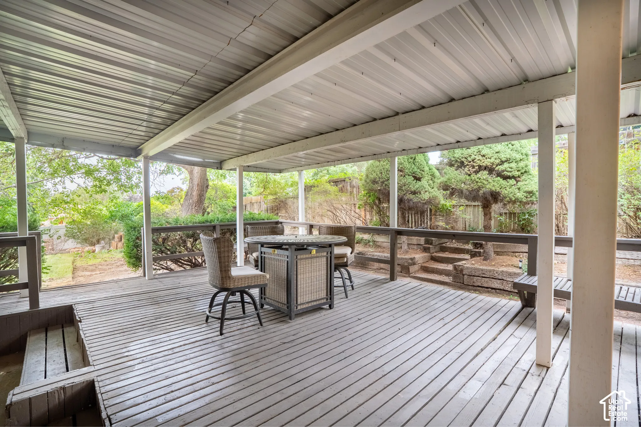 Expansive covered deck featuring a metal roof, wood flooring, and wood railings