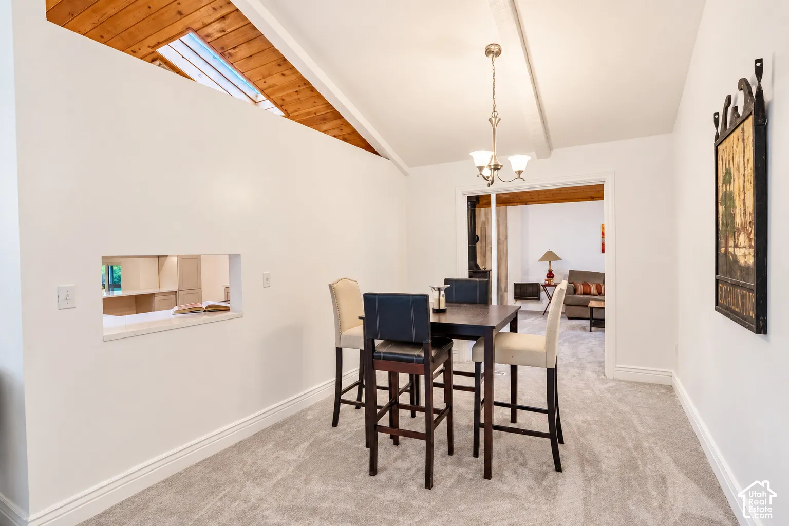 Vaulted wood-finish ceiling with skylight, recessed wall opening with stone-finish ledge, recessed lighting, carpeted flooring, and a chandelier light fixture
