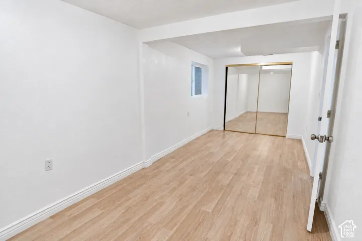 Wood-finish flooring, white walls, and mirrored closet doors with new paint