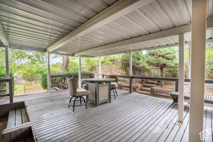 Expansive covered deck featuring a metal roof, wood flooring, and wood railings