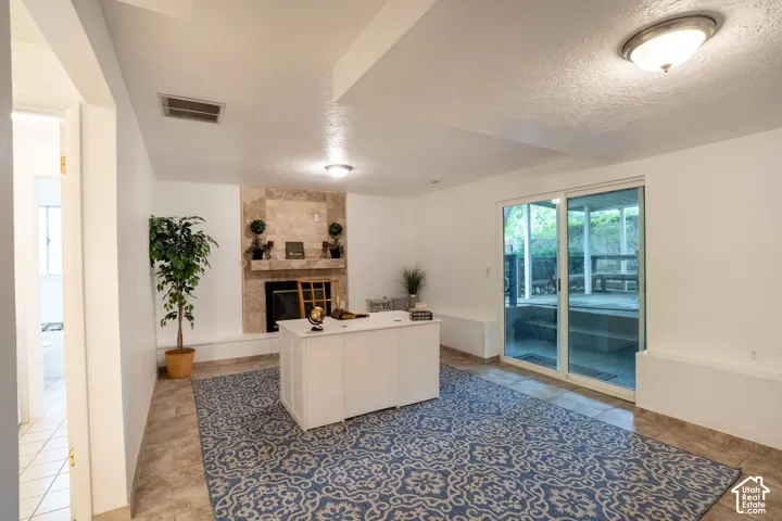 Tiled flooring throughout the main area, featuring a gas fireplace and remodeled hearth, recessed ceiling lighting, and a new sliding glass door leading to an outdoor covered deck