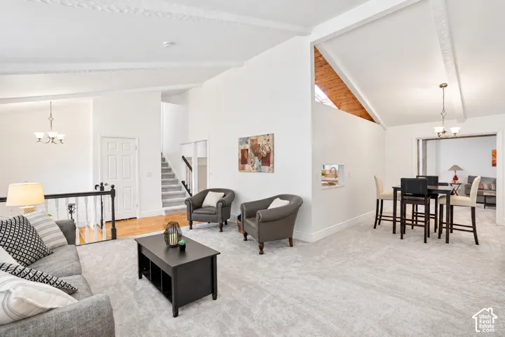 Vaulted ceilings with exposed beams, light gray carpeting, and new paint