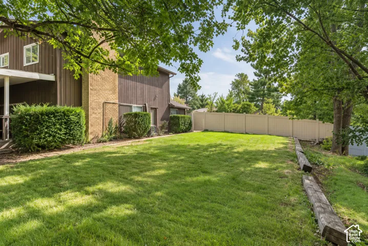 Expansive lawn area with mature trees, privacy fencing, and a retaining wall, and new sod