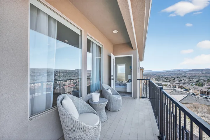 Balcony with wood-finish flooring, black metal railings, and a stucco exterior
