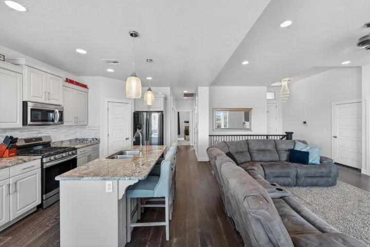 Kitchen featuring light cabinetry with stainless steel appliances, granite countertops, and a full-height tile backsplash