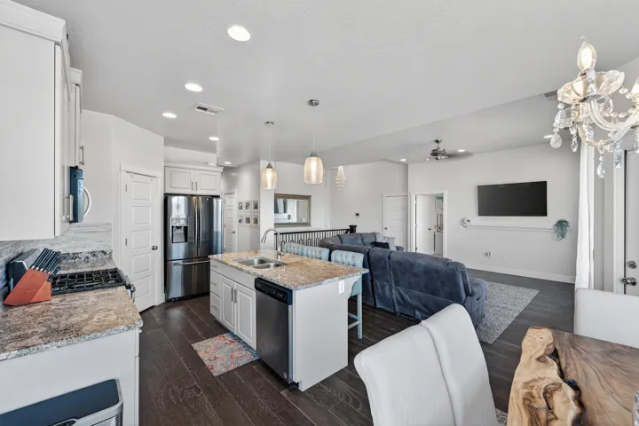 Open concept living space featuring wood-finish flooring, recessed lighting, and a kitchen island with a sink and pendant lighting