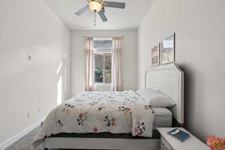 Window with light-toned drapes, ceiling fan with integrated lighting, and light-colored walls