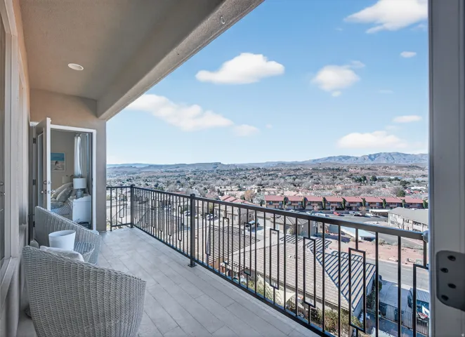 Expansive balcony featuring a decorative metal railing, wood-finish flooring, recessed lighting, and a broad cityscape