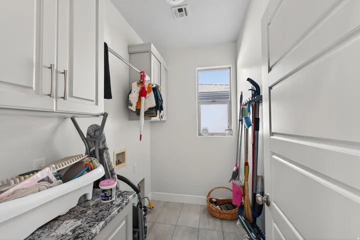 White cabinetry with brushed nickel hardware, light-toned tile flooring, and a single window