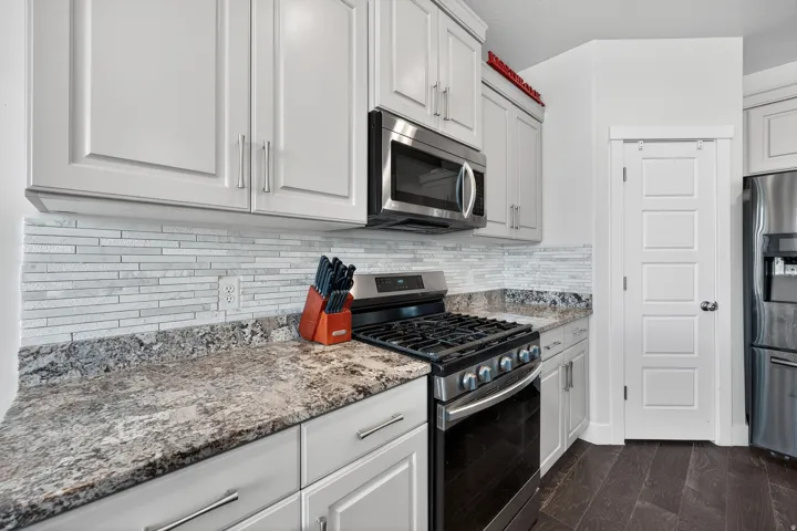 Kitchen featuring light-toned cabinetry, a mosaic tile backsplash, and dark wood-finish flooring