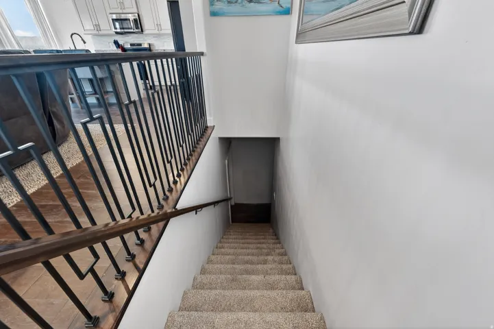 Stairway with carpeted treads and a handrail, featuring a wrought iron baluster system