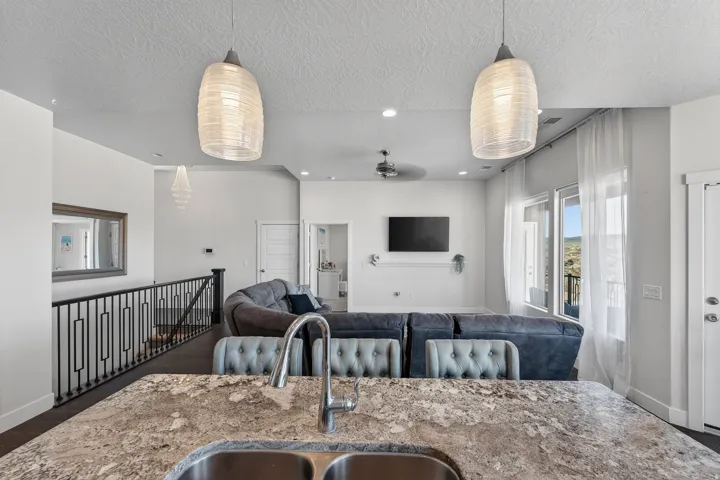 Kitchen island with a double basin stainless steel sink, dual contemporary pendant lights, and a ceiling fan