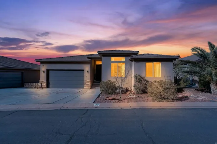 Contemporary stucco exterior with a flat roofline, integrated two-car garage, concrete driveway, and low-maintenance landscaping
