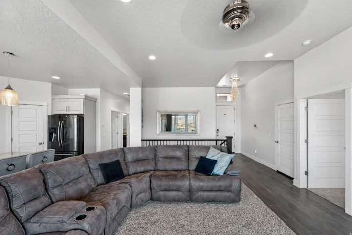Open concept living area featuring dark wood-finish flooring, white paneled doors, recessed lighting, and a modern ceiling fan
