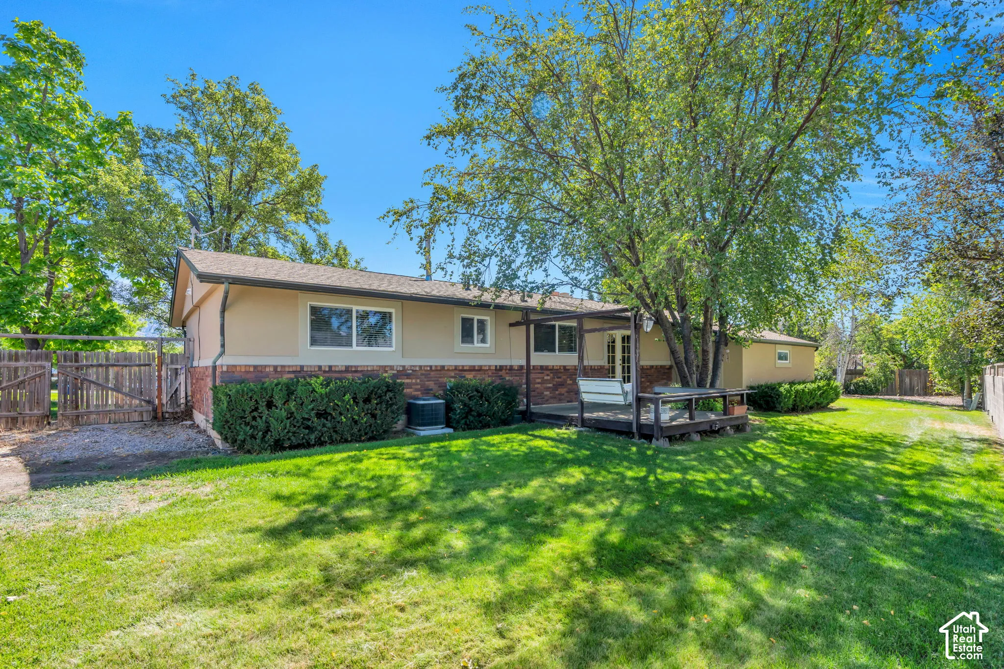 Expansive green lawn, mature trees, wood privacy fence, and a wood deck