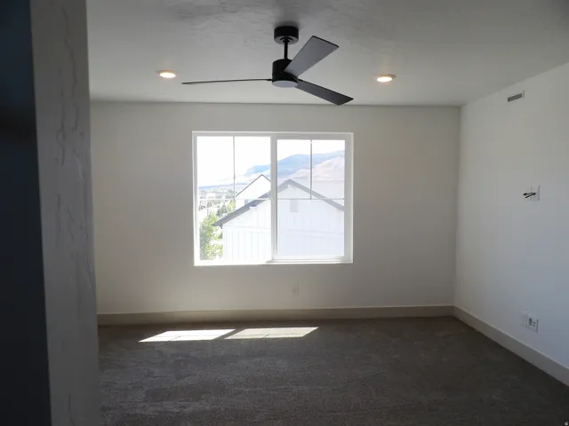 Recessed lighting, ceiling fan, white walls, large window, and carpeted flooring