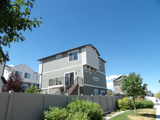 Multi-level exterior with siding, a rear balcony, and a ground-level patio