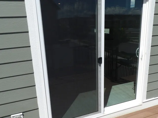 Sliding glass door with white frame and black hardware, featuring an integrated screen