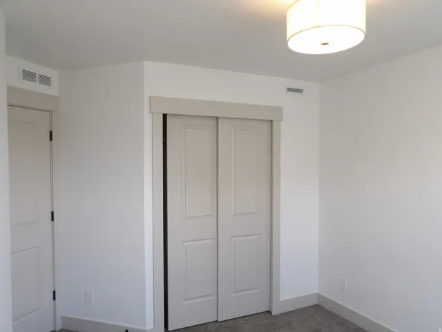 White painted walls with a drum ceiling light fixture, bi-fold closet doors, and carpet flooring