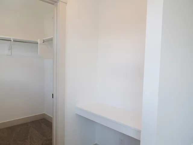 Built-in desk surface with a crisp white finish and a dedicated closet with a hanging rod