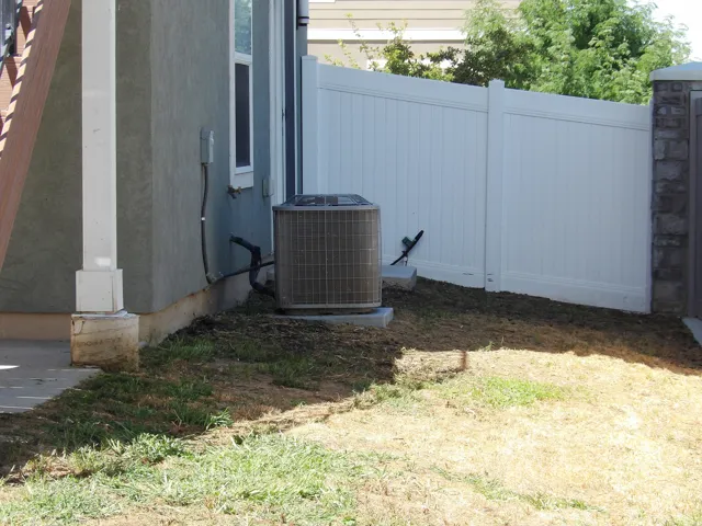 Stucco exterior with a white vinyl privacy fence and a stone pillar