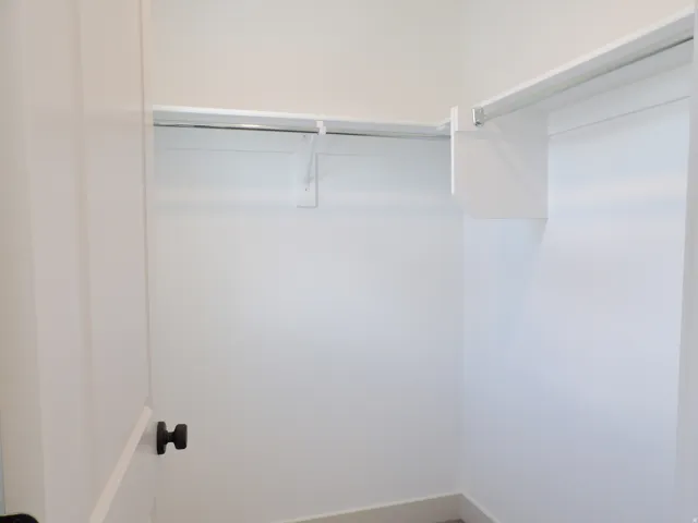 White interior door with black hardware, white walls, and built-in closet shelving and rods