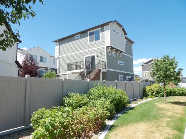 Multi-level exterior with siding, a balcony with black railings, and a lower-level patio door