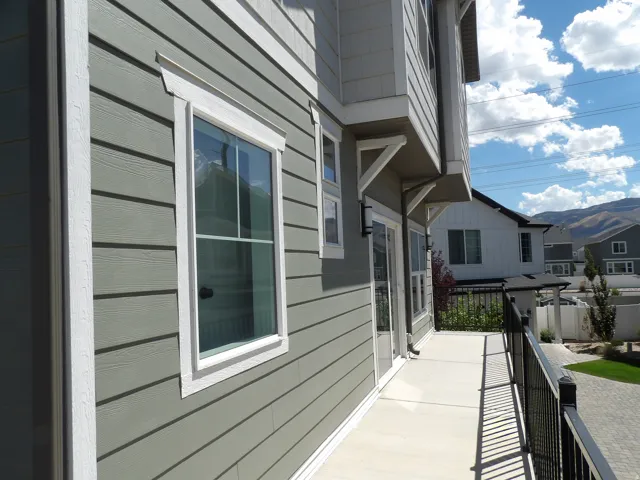Exterior siding with white trim, private balcony with black metal railing, and glass sliding door