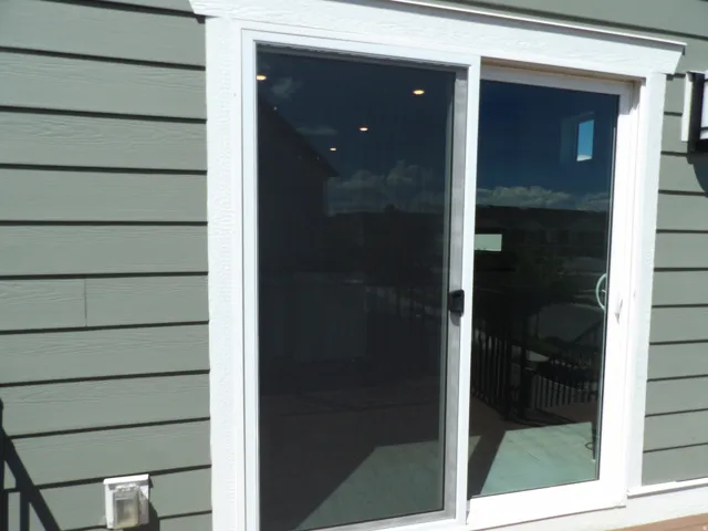 Sliding glass door with screen, white trim, and light green horizontal siding