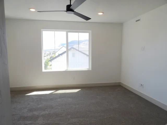 White walls, gray carpet, and a large window with a distant mountain backdrop